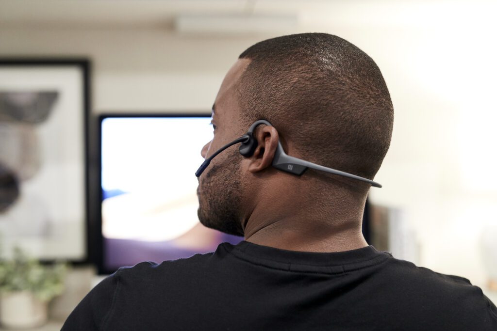 AfterShokz OpenComm headset -- bone conduction technology delivers sound through user's cheekbone, leaving ears open so you can hear your surroundings.