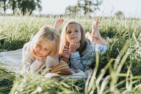 little girls lying on green grass field